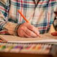 Person drawing in coloring book using colored pencils