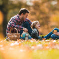 Parents and child sitting on blanket outdoors during fall season