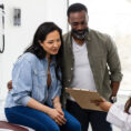 Couple talking with a doctor who is showing them a clipboard with information