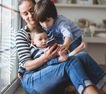 Parent with two children in their lap looking at a mobile phone