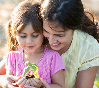 Mother and daughter holding a small plant in a pot