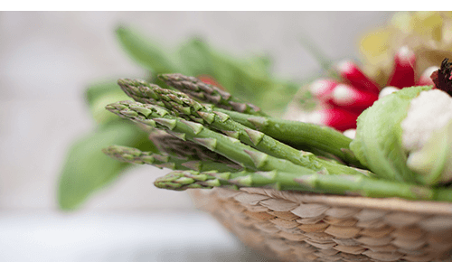 Closeup of asparagus spears in a basket full of vegetables