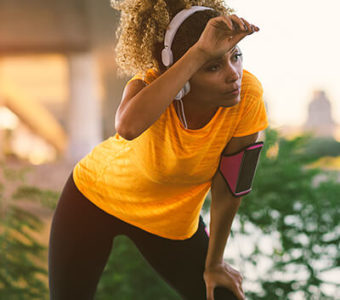 Person wiping forehead while resting during a sunny run outside