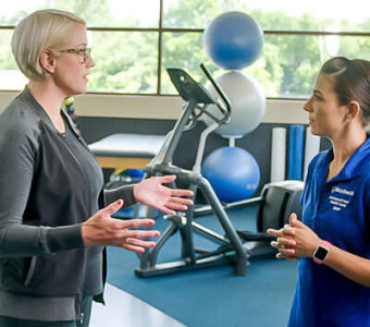 Woman talking to an Exercise Physiologist on a running track in a gym