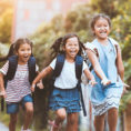 Children holding hands and wearing backpacks on their way home from school