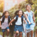 Children holding hands and wearing backpacks on their way home from school