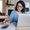 Woman looking at paperwork while working on computer