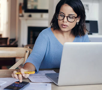 Woman looking at paperwork while working on computer