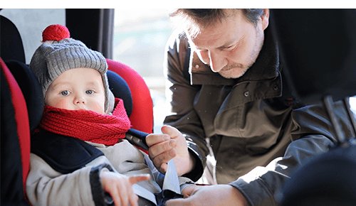 Father adjusting car seat with infant sitting in it