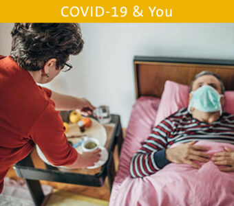 Person bringing food to their loved one sick in bed with a mask on