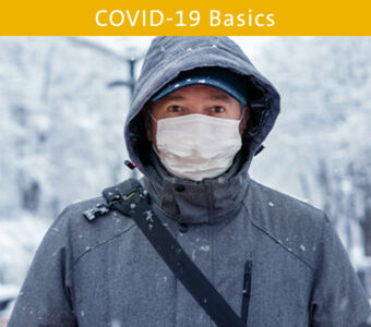 Man standing outside in snow wearing a face mask