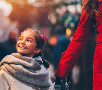 Mother and child holding hands and looking at holiday lights