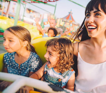 Adult and two children on rollercoaster ride at fair