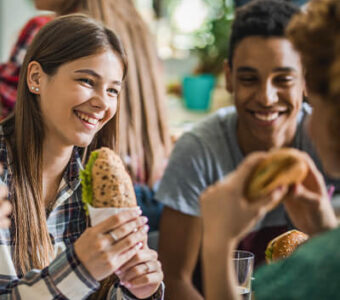 Group of young adults eating sandwiches