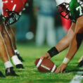 Closeup of football between two teams on football field during high school football game