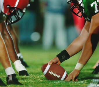 Closeup of football between two teams on football field during high school football game