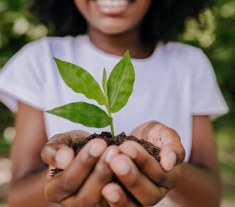 Young adult holding a plant outside