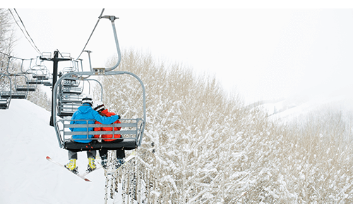 Couple on Ski Lift above snow covered mountain