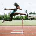 Teen running hurdles on track