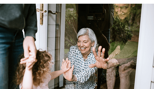 Family visiting each other but keeping separated for safety by glass door