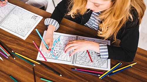 Person coloring in coloring book with colored pencils