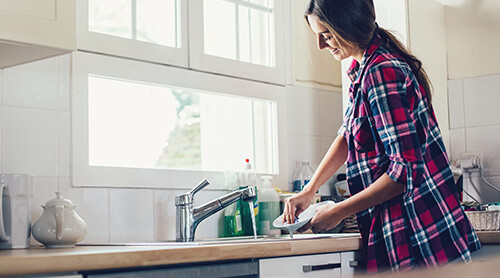 Woman washing dishes at kitchen sink