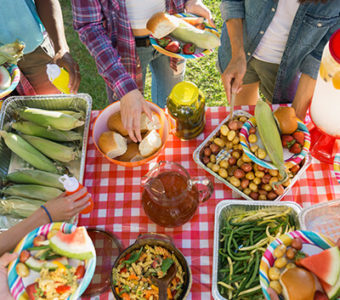 Overhead shot of potluck spread out on table with people around it