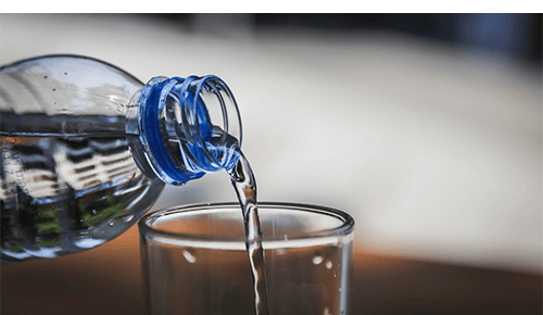 Bottle pouring water into glass