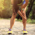 Woman bending over and holding knee with hands on pathway outside