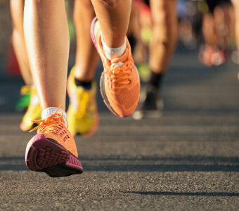 Close up of runner's feet in motion in front of a group of other people running