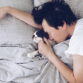 Person sleeping in bed next to small animal