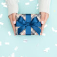 Person holding gift wrapped in blue bow and paper