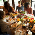 Family sitting around a table full of Thanksgiving food dishes