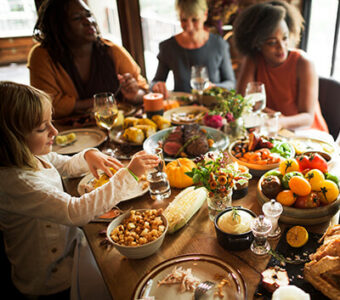 Family sitting around a table full of Thanksgiving food dishes