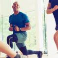 Man performing lunge exercise with kettlebell in workout class