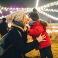 Mother and child kissing under holiday lights