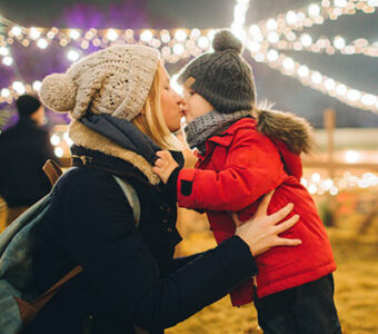 Mother and child kissing under holiday lights