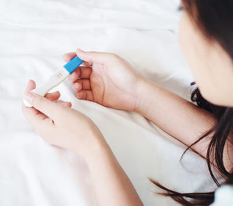 Woman holding and looking at a pregnancy test