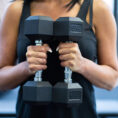 Woman holding two dumbbells in a gym