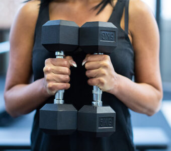 Woman holding two dumbbells in a gym