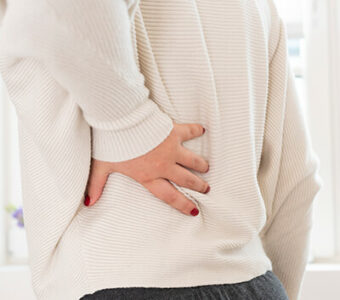 Closeup of person holding their lower back in pain