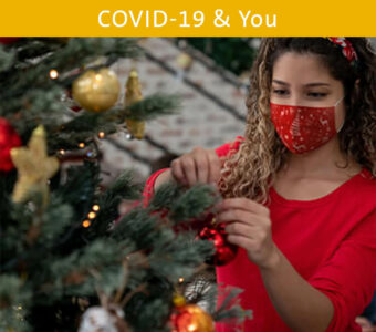 Woman wearing face mask decorating Christmas tree