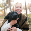 Woman smiling hugging dog outside