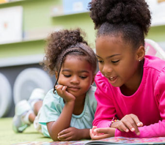 Two children reading a book together in a library