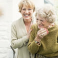 Middle-aged woman hugging older woman, both smiling