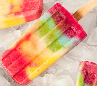 Rainbow colored popsicles sitting on ice