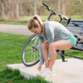 Molly sitting on a bench tying her shoes with a bike next to her