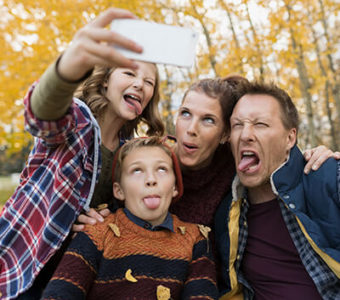 Family outside during the fall making funny faces while taking a picture of themselves