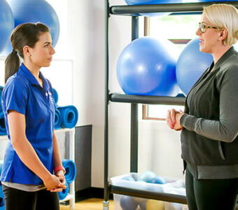 Woman talking to exercise physiologist in gym