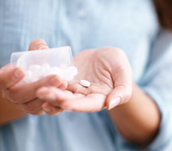 Closeup of hand shaking pills out of a bottle